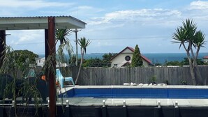 A swimming pool with a wooden deck, a covered area, and a view of the ocean. - The Sky House by the bay (Wynnum)