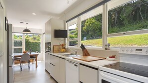 Una cocina moderna con un gran ventanal, una zona de comedor y un horno empotrado.