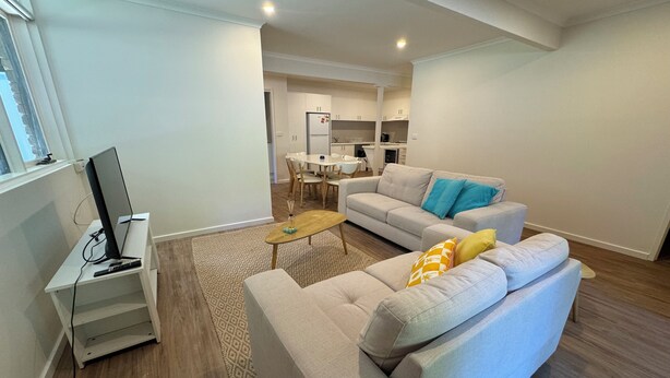 A modern living room with a sofa, a coffee table, and a TV on a stand. - 3 Bedroom, pet friendly unit, 2min walk from main street, beach and supermarket. (Lorne)