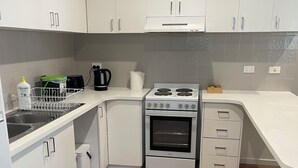 A modern kitchen with white cabinets, a built-in oven, and a stainless steel sink. - 3 Bedroom, pet friendly unit, 2min walk from main street, beach and supermarket. (Lorne)