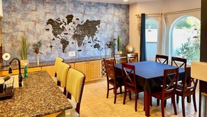 Un comedor con un mural de un mapa mundial, una cocina con encimeras de granito y una mesa de comedor con sillas.