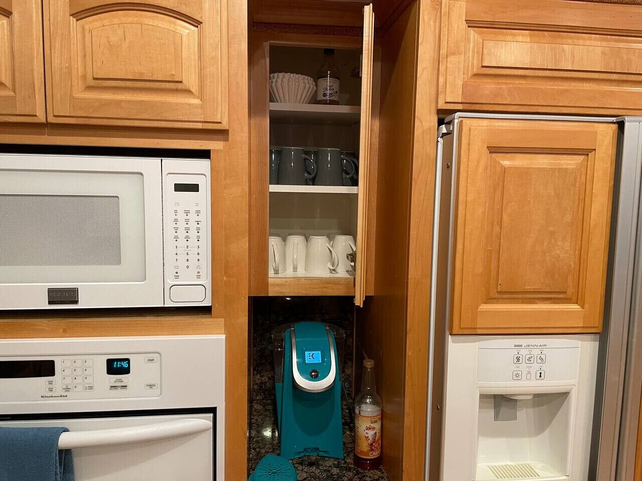 A compact kitchen with a microwave, coffee maker, and a refrigerator.