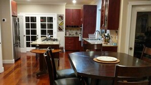 A spacious dining area with a wooden table and chairs, a kitchen with wooden cabinets, and a refrigerator.