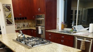 A kitchen with granite countertops, stainless steel appliances, wooden cabinets, and a built-in island with a placemat.