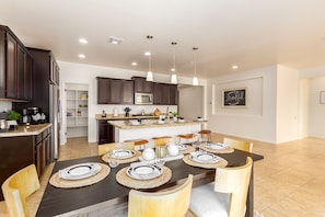A modern kitchen with dark cabinets, a central island, and pendant lighting.