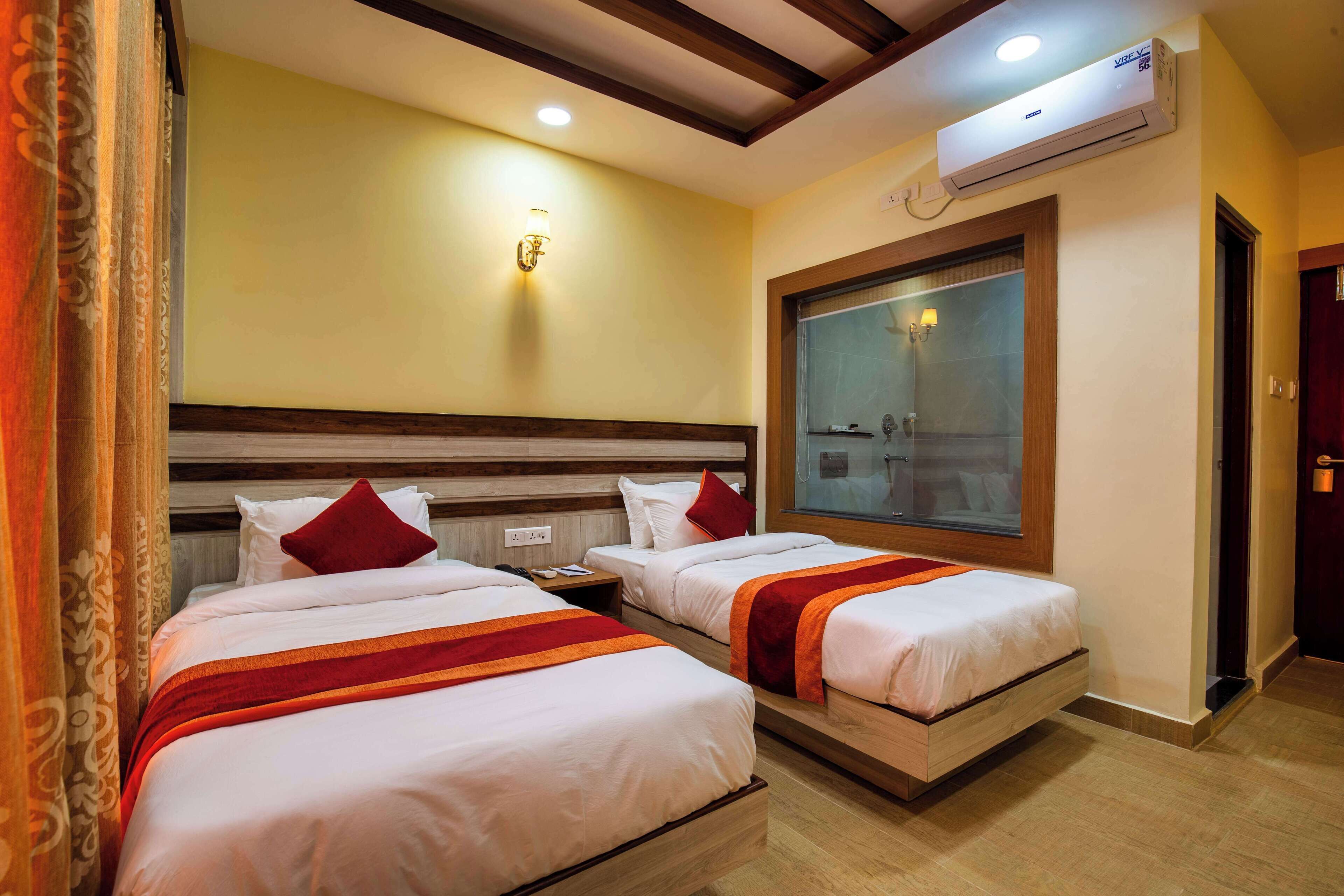Habitación de hotel con dos camas, un ventanal grande y un equipo de aire acondicionado.