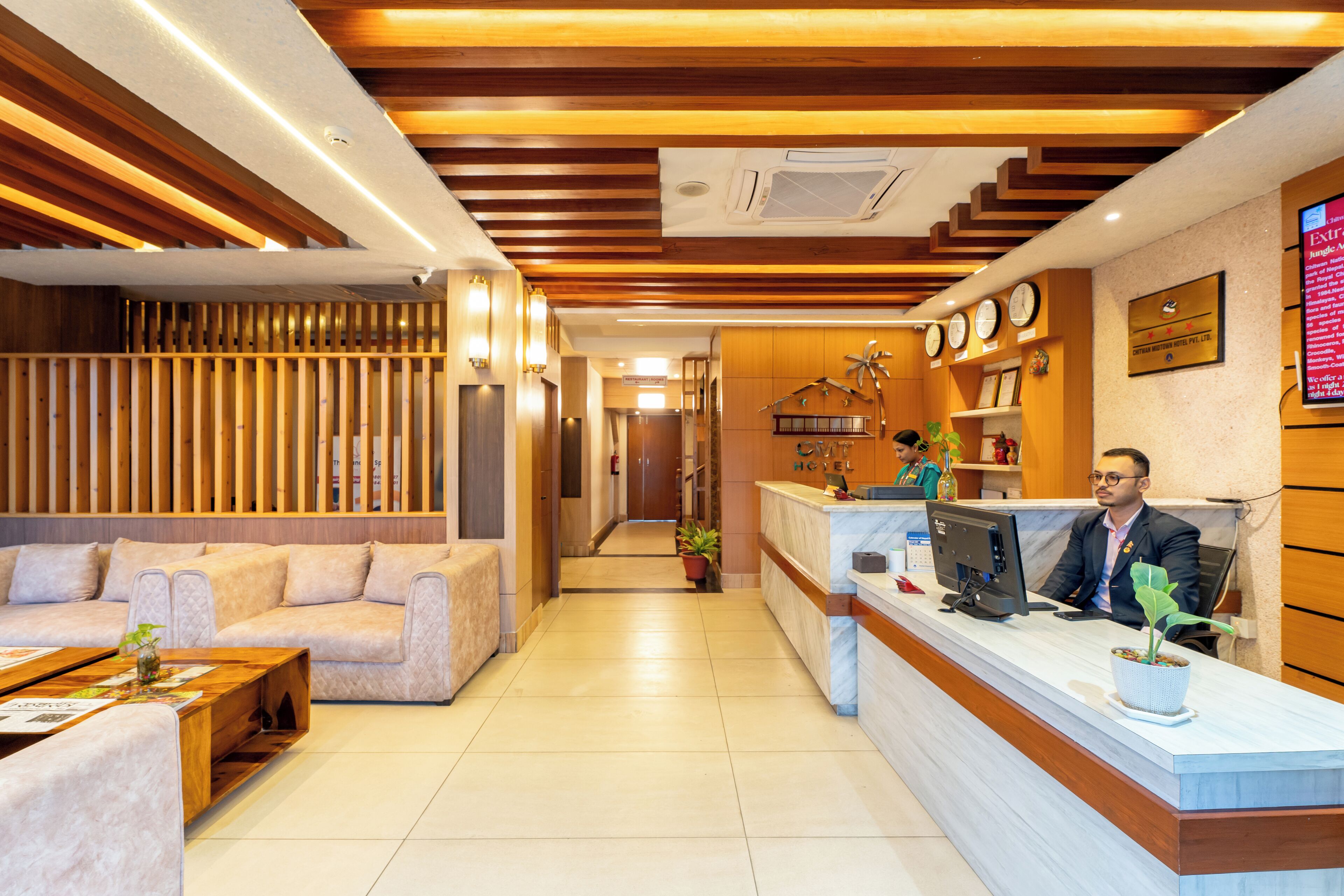 A hotel reception area with a wooden reception desk, a sofa, and a reception counter.