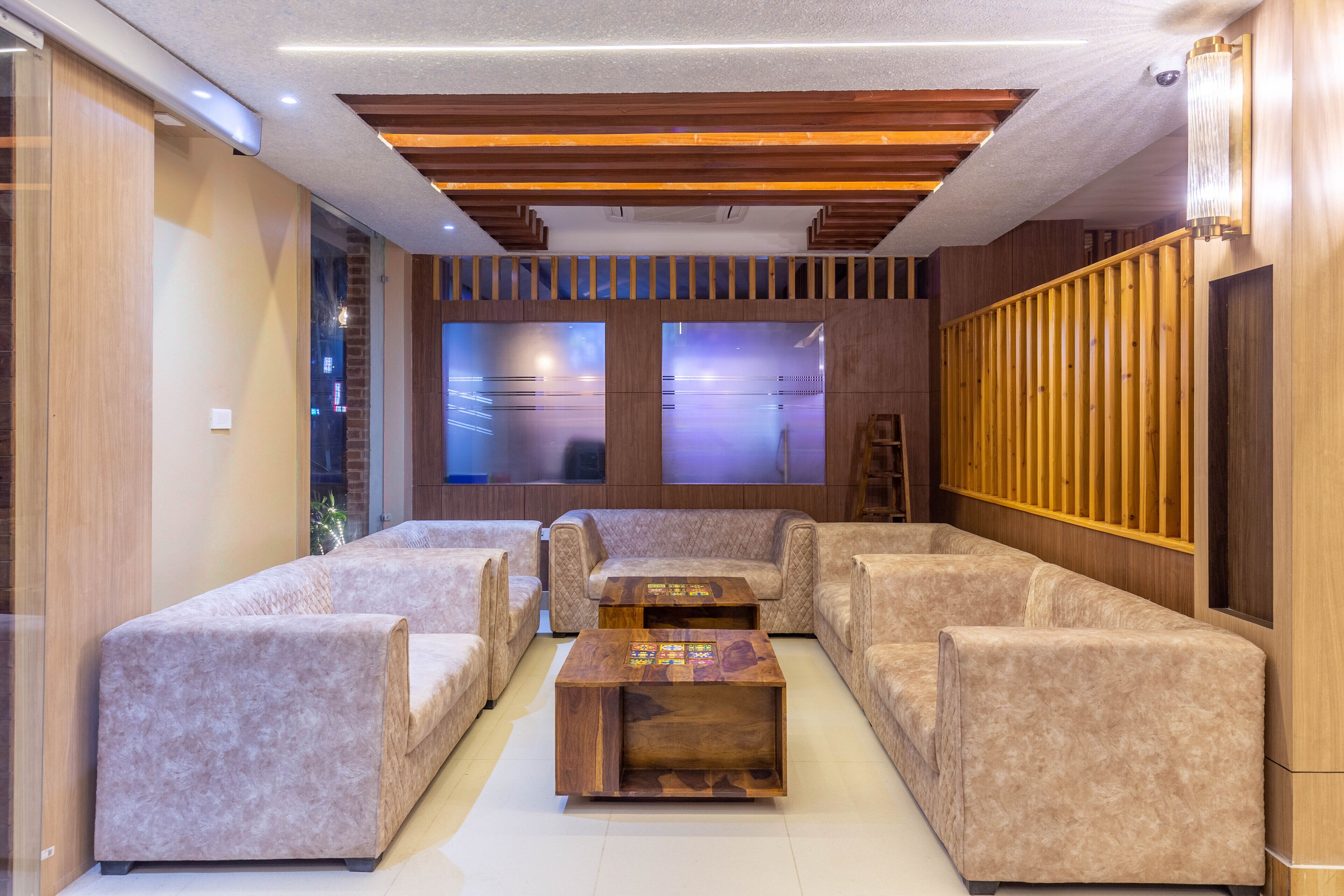 A modern living room with a wooden ceiling, a central coffee table, and beige sofas.