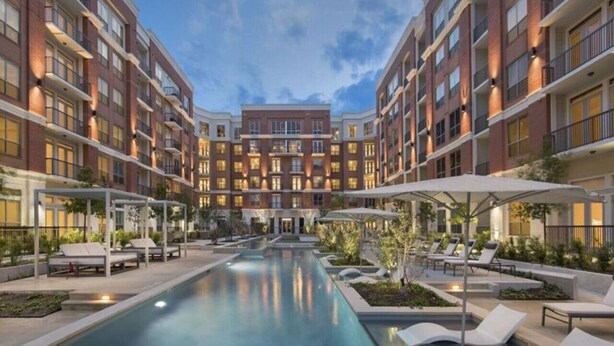 Et moderne hotel med central pool, loungeområder og flere etager med murstensbygninger.