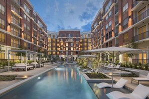 A modern hotel with a central pool, lounge areas, and multiple floors of brick buildings. - Spacious 2 bed/ 2 bath Apartment in Spring, TX (Spring)