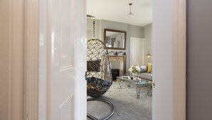 Une pièce avec un fauteuil suspendu, une table basse en verre et un miroir au mur.