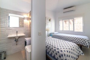 A room with a sink, two beds with patterned bedding, a window, and an air conditioning unit. - Holiday Home "Beach-Front Bahía Dorada" with Sea View, Shared Pools and Wi-Fi (Estepona)