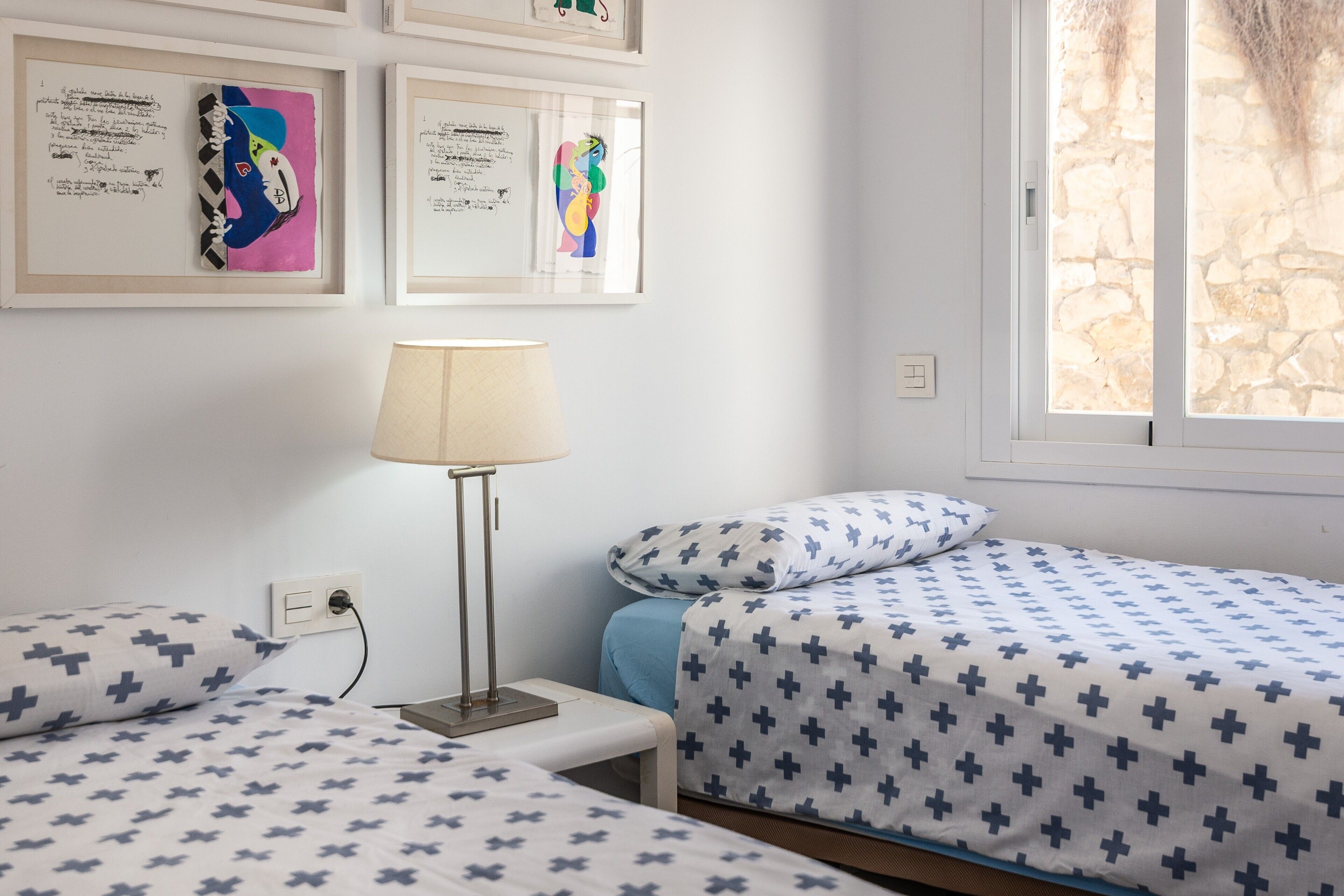 Een kamer met twee bedden, een nachtkastje, een lamp en lijstwerken aan de muur.