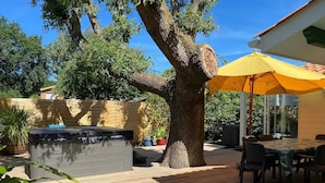 A wooden deck with a hot tub, outdoor furniture, and a yellow umbrella. - Villa pool & SPA on the Arcachon basin (Lanton)