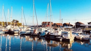 A marina with multiple sailboats docked, surrounded by small buildings with red roofs. - Villa pool & SPA on the Arcachon basin (Lanton)