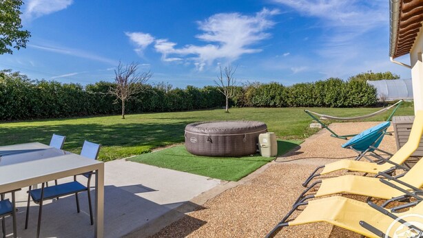 Une terrasse avec une table et des chaises, un hamac et un grand espace extérieur aménagé pour s’asseoir.