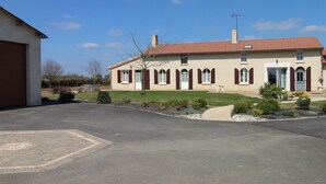 Une maison à deux étages, avec un toit recouvert de tuiles rouges, une porte d’entrée et un garage.