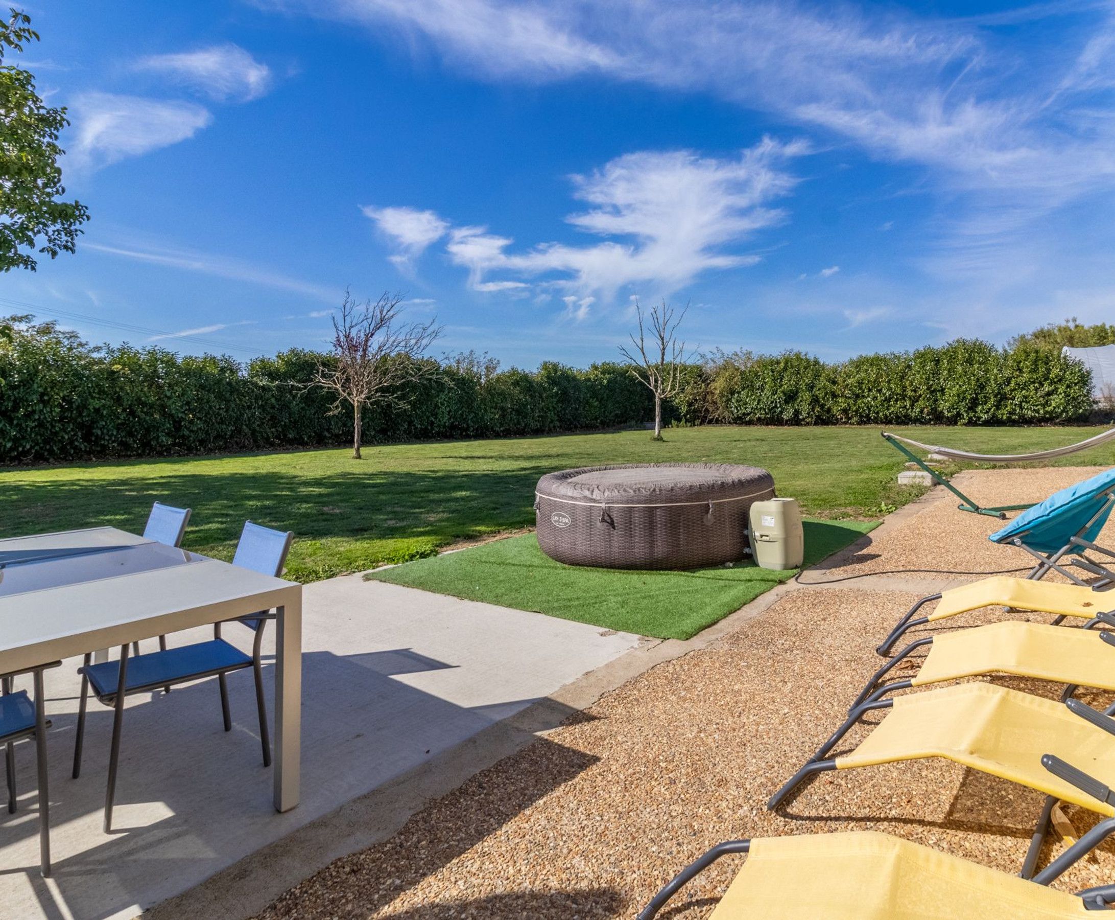 A patio with a table and chairs, a hammock, and a large outdoor seating area.