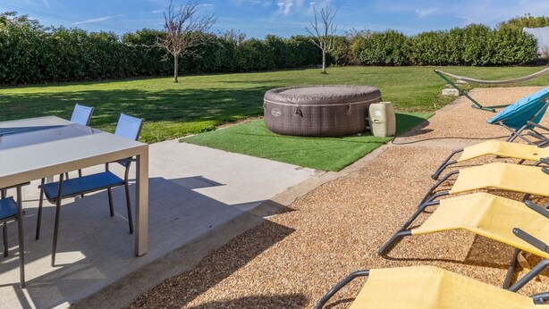 Un patio con tavolo e sedie, un'amaca e un'ampia zona relax all'aperto.