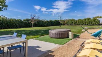 A patio with a table and chairs, a hammock, and a large outdoor seating area.