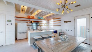 A modern kitchen with white cabinetry, a central island, and a 'BIG CHILL' sign. - Home in Downtown with Shared Pool, Near Beach, Golf Cart Access (Port Aransas)