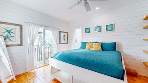 A bedroom with a bed, a ceiling fan, and a view through a glass door.