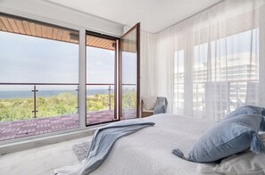 A bedroom with a large bed, a view of the sea, and a balcony with a wooden deck. - Apartamenty Swinoujscie BalticPark Plaza (Swinoujscie)