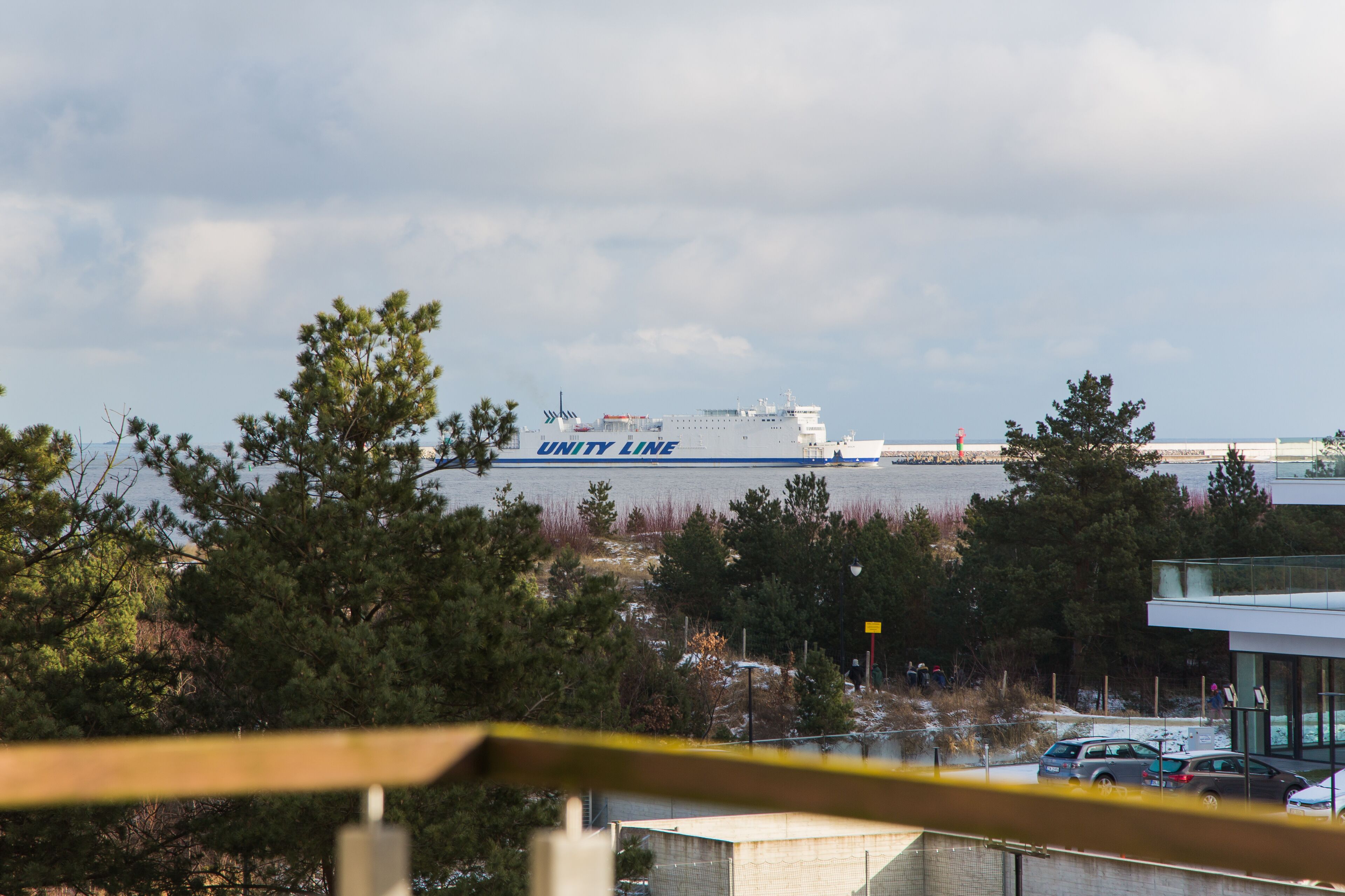 Un grand navire portant l’inscription « UNITY LINE » sur sa coque était amarré près d’un bâtiment à la façade en verre.