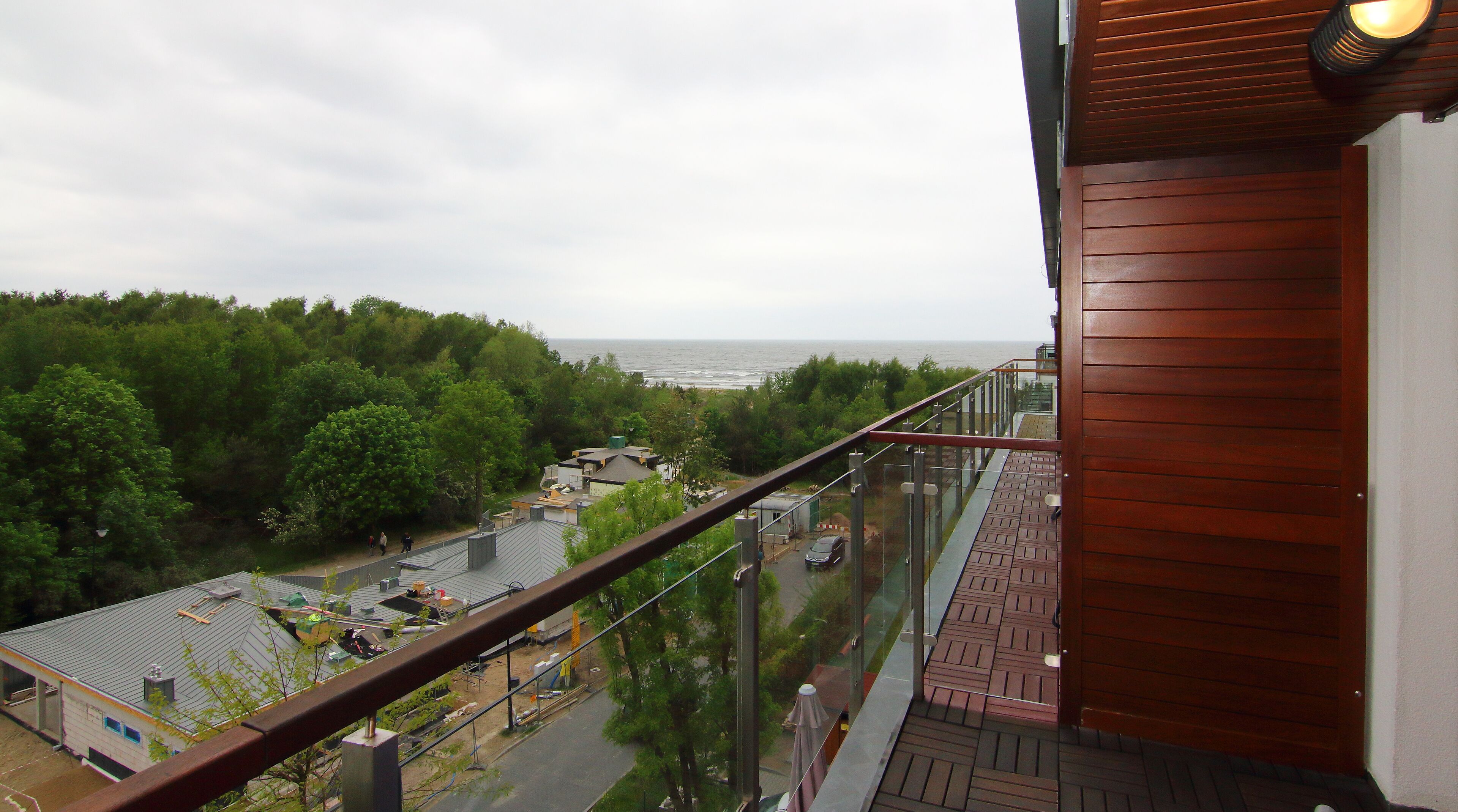A balcony with a view of the sea and a forested area.