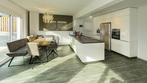 A modern kitchen with a central island, built-in appliances, and a dining area with a sofa and table.