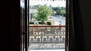 Une porte donnant sur un balcon d’où l’on peut admirer une rue et des arbres.