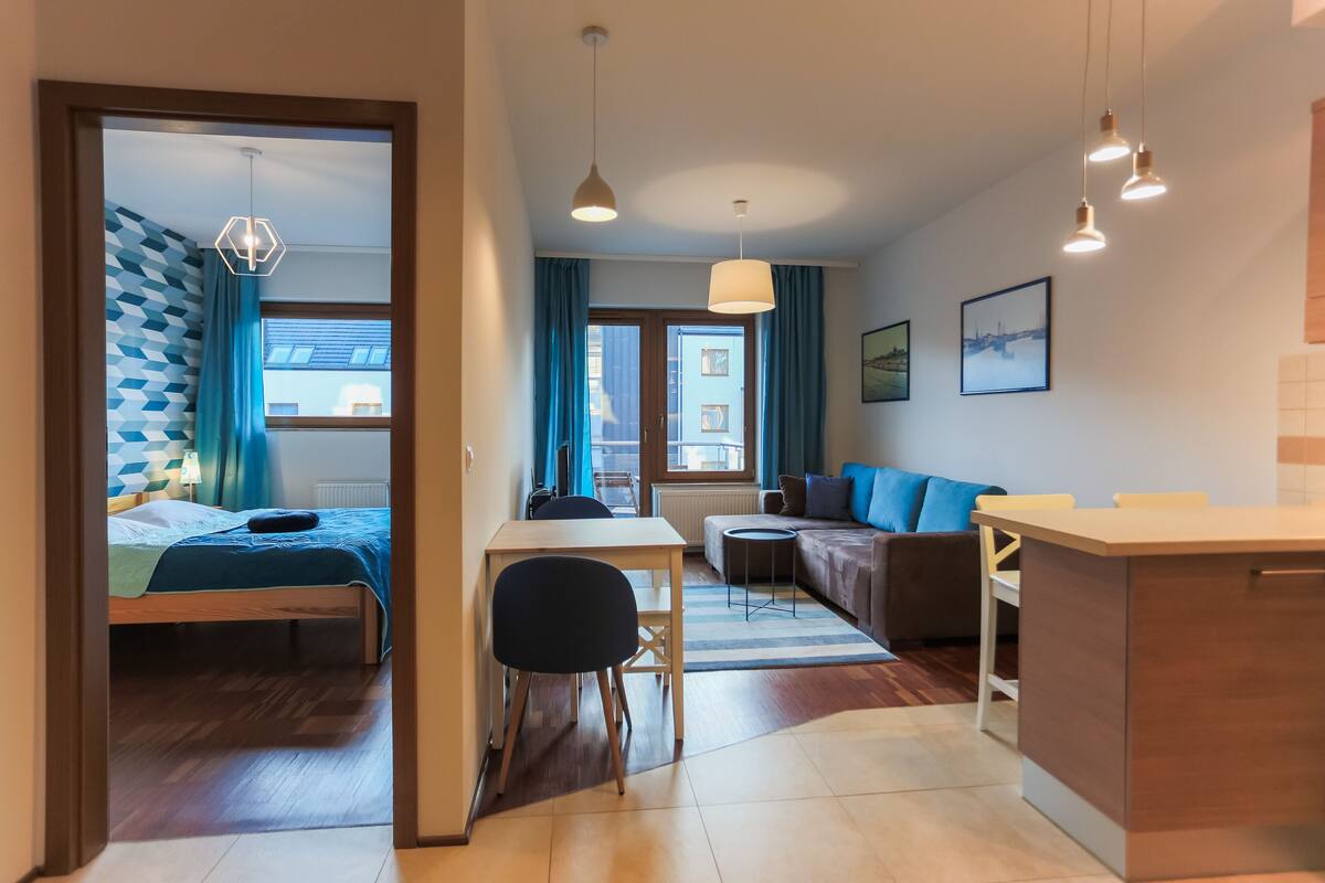 Una habitación de hotel moderna con cama, una mesa de comedor, un sofá y una zona de cocina.