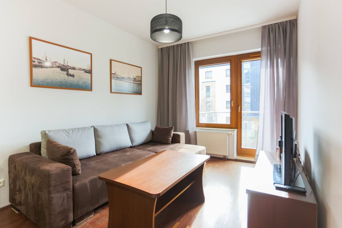 Una sala de estar moderna con un sofá marrón, una mesa de centro de madera y dos cuadros enmarcados en la pared.