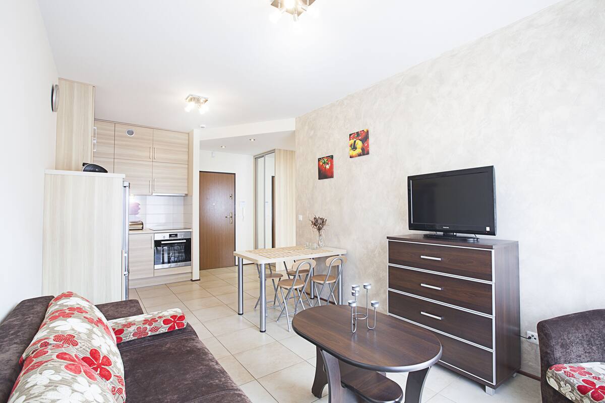 Una sala de estar moderna con sofá, mesa de comedor y televisor.