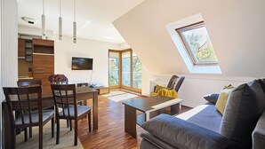 Et moderne opholdsrum med spiseplads, sofa, fjernsyn og ovenlysvindue.