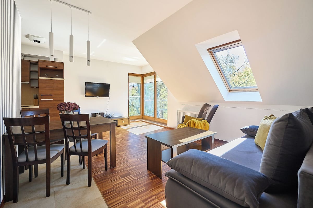 Un espacio habitable moderno con comedor, sofá, televisor y tragaluz.
