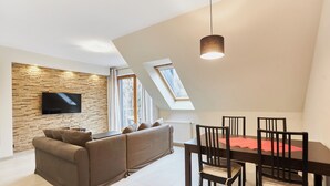 Una sala de estar moderna con una pared de piedra, un televisor de pantalla plana, un sofá y una mesa de comedor con sillas.