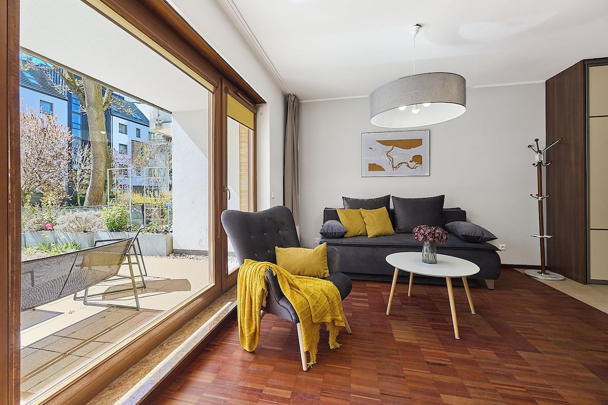 Un salón moderno con sofá, una mesa de centro y un gran ventanal con vistas a un jardín.