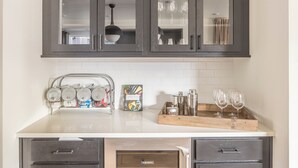 Una cocina con armarios oscuros, una encimera blanca y una alacena para vinos.