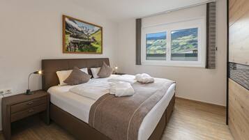 A bedroom with a bed, nightstand, lamp, and a window with a view of a landscape.