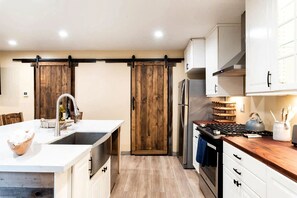 A modern kitchen with a central island, a double door, and a built-in oven. - Main House + Guest House · Spa · Game Room (Big Bear)