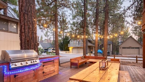 An outdoor patio with a barbecue grill and wooden benches.
