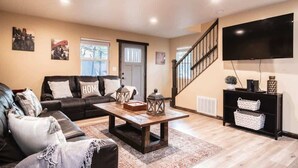 A living room with a sofa, coffee table, and a TV mounted on the wall.