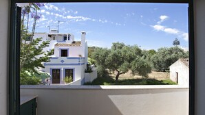 A view of a building with a white facade and blue accents, surrounded by greenery and trees.