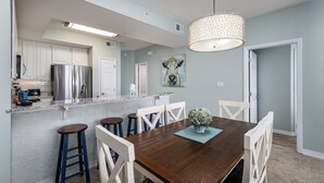 Uma cozinha moderna com eletrodomésticos de aço inoxidável, uma mesa de jantar de madeira e banquetas de bar.