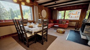 A dining area with a wooden table set for four, a sofa, and a fireplace. - Located in Les Collons 1850, only 50 meters from the ski-lifts "La Joc" and "Petit Vallon" (crossbow (Thyon-Les Collons)
