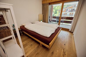 A bedroom with a wooden bed, a white wardrobe, and a view of a balcony with outdoor furniture. - Located in Les Collons 1850, only 50 meters from the ski-lifts "La Joc" and "Petit Vallon" (crossbow (Thyon-Les Collons)