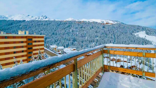 Eine verschneite Berglandschaft mit einem Holzbalkon.