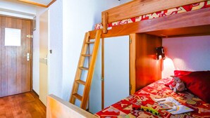 Ein Stockbett mit einer Leiter, einer Holztür und einer Wandleuchte.