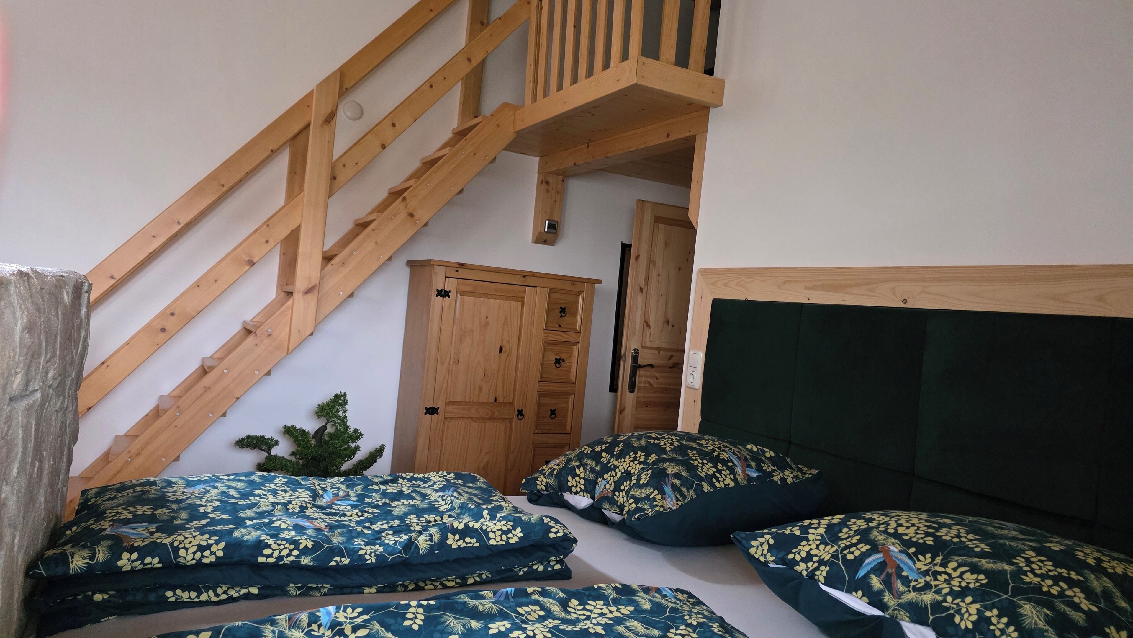 Ein Schlafzimmer mit einer Holztreppe, einem Bett mit floralem Bettzeug und einem kleinen Topfpflanzen.